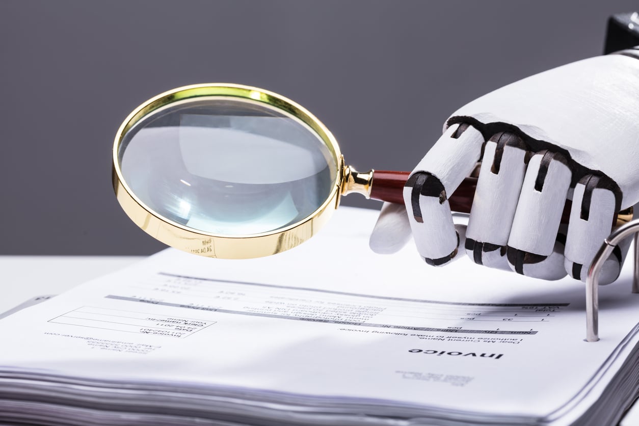 robot hand holding a magnifying glass on an invoice