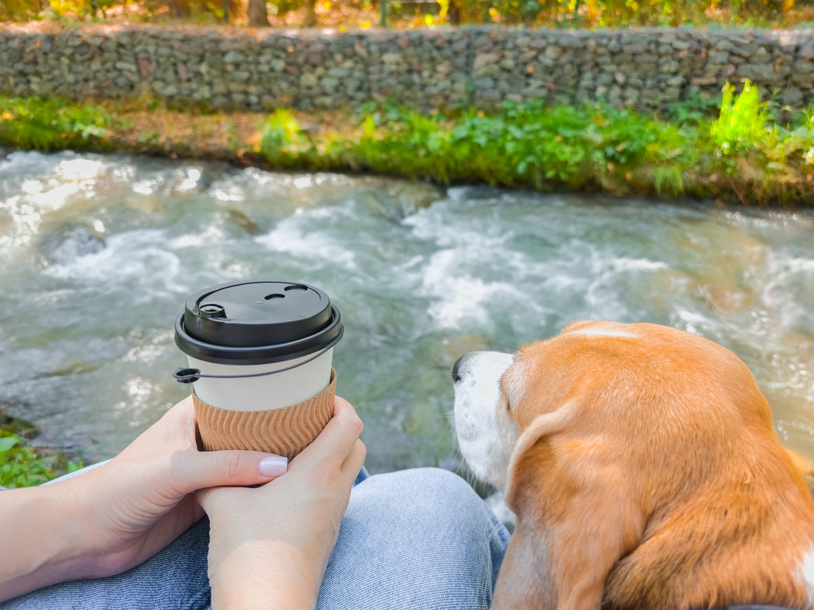 Woman holding coffee cup with dog